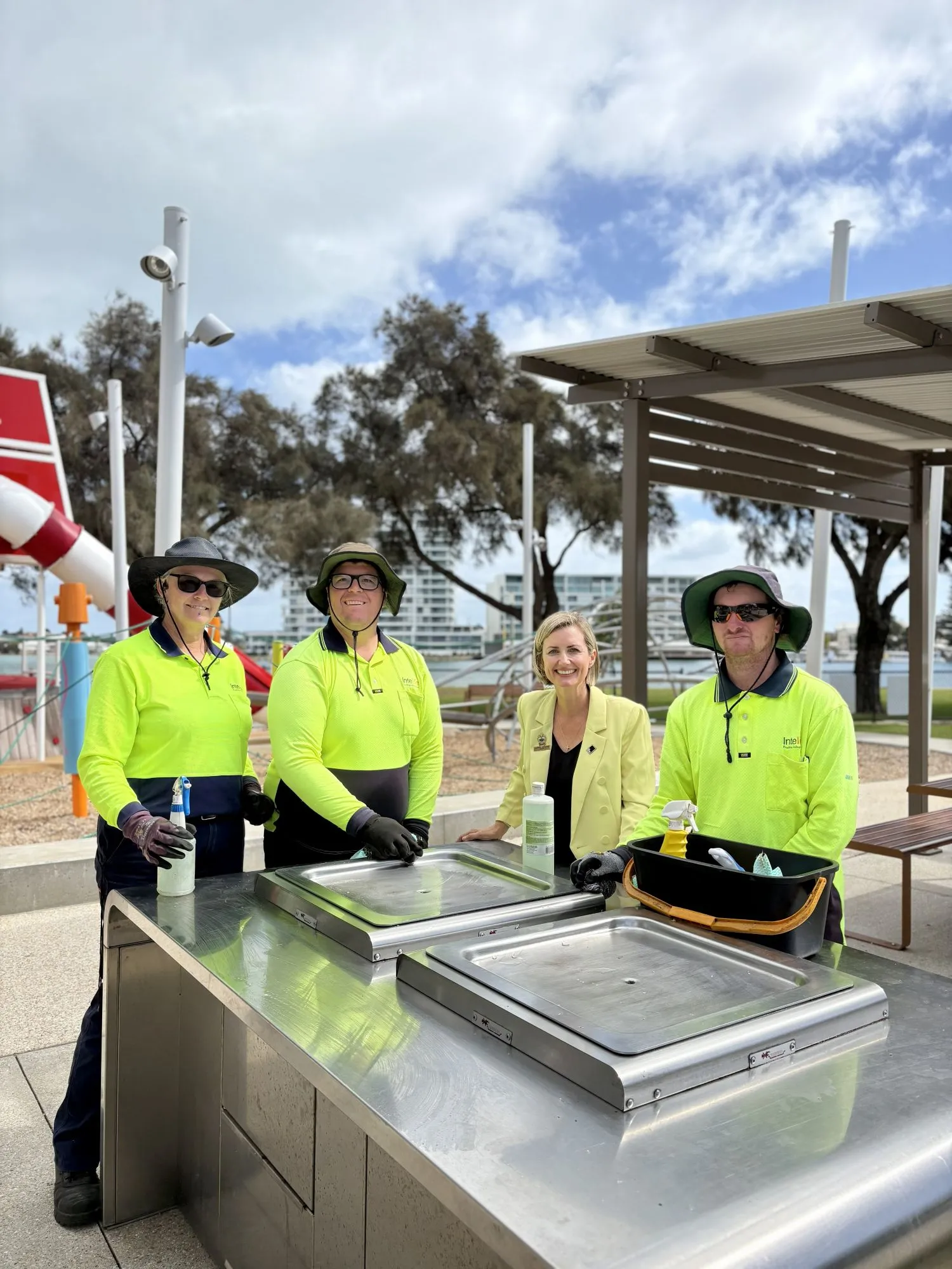 Mayor Kearns with Intelife staff standing at BBQ on foreshore.